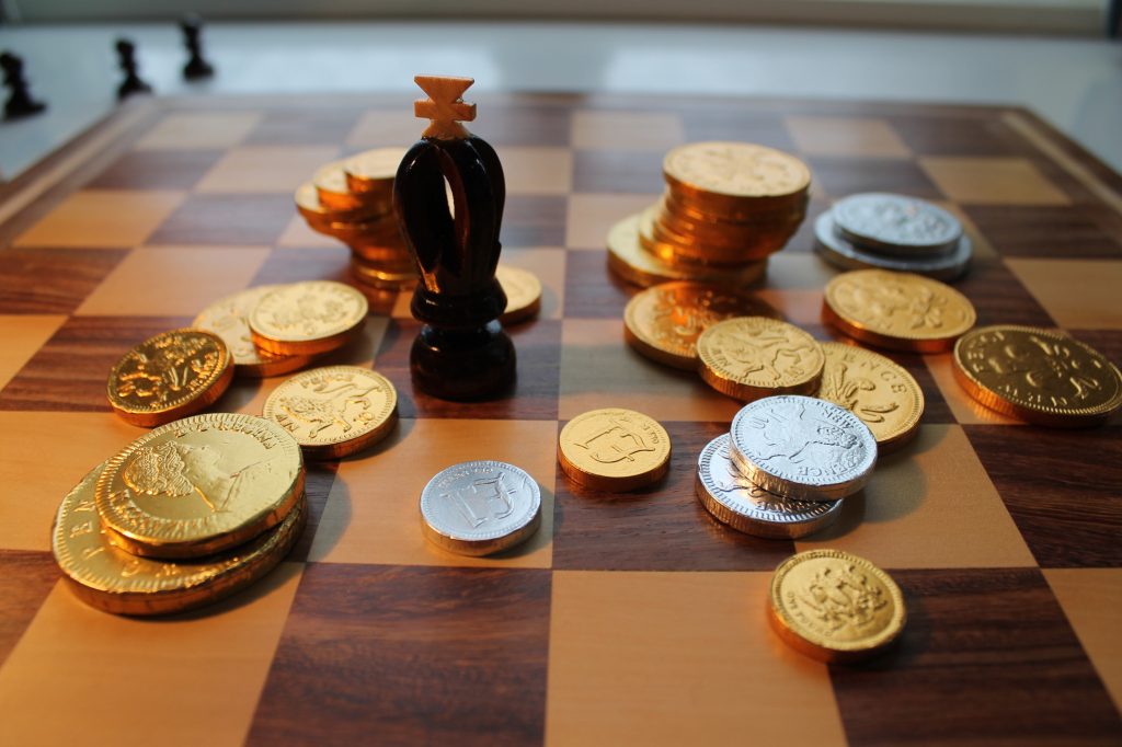 Chess king and chocolate coins on chessboard.